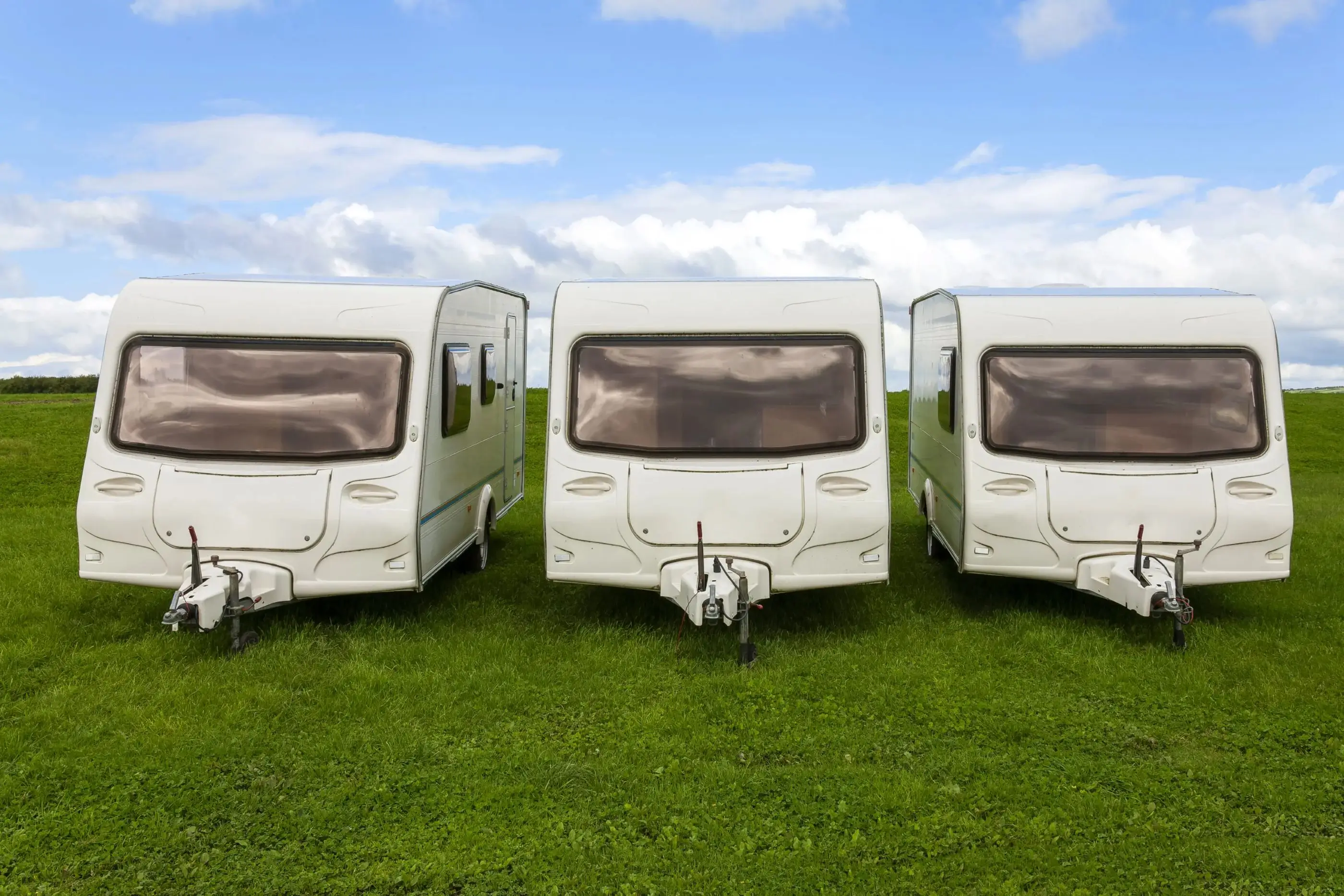 Three white caravans on green grass